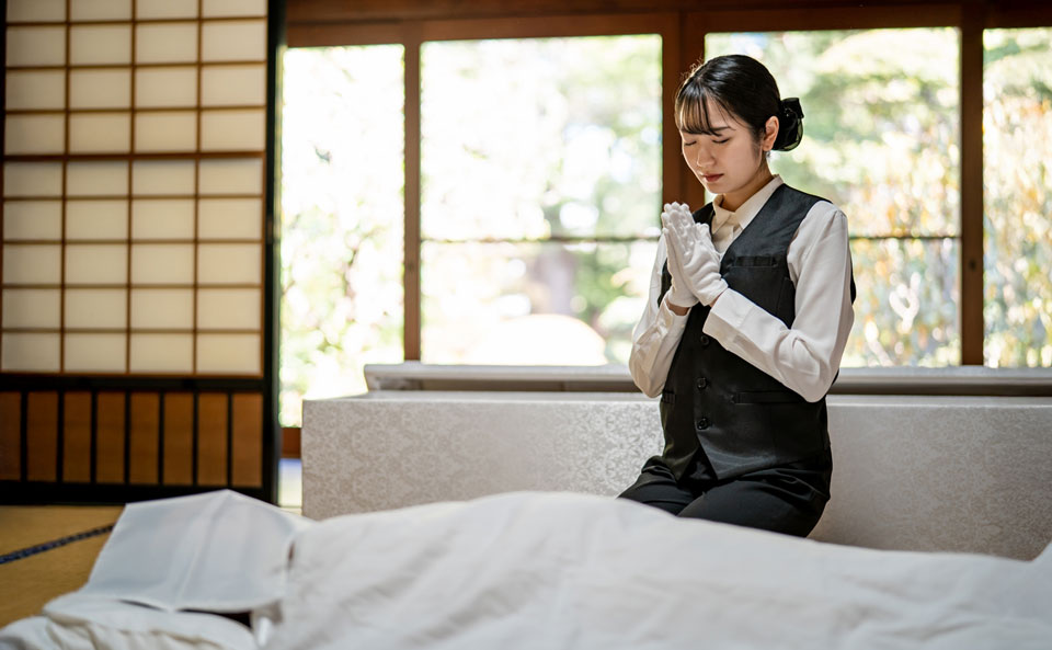セレモニーハート西大島ホールが江東区で和室に安置された遺体の前で手を合わせる女性スタッフ