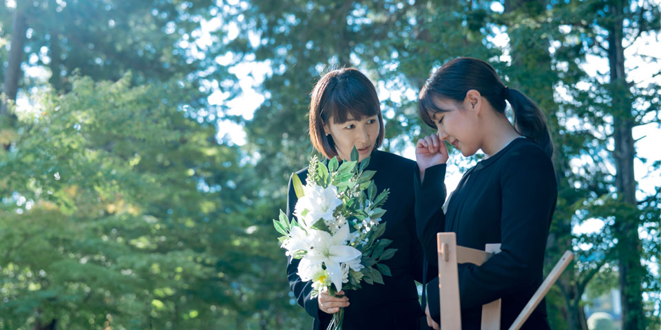 セレモニーハート西大島ホールが江東区の屋外で白い花束を持つ喪主に寄り添うシーン